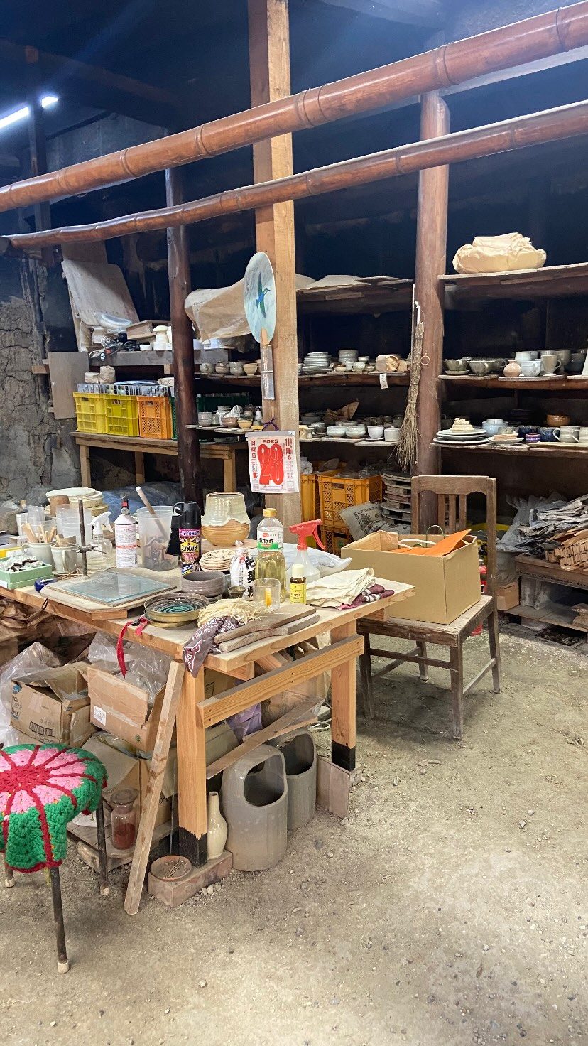 大塩正人窯の仕事場。作業台に道具、棚に焼く前の器が並ぶ